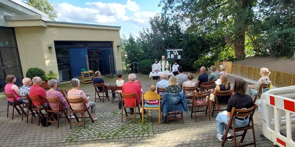 Vor dem Kircheneingang sitzen die Gottesdienstbesucher